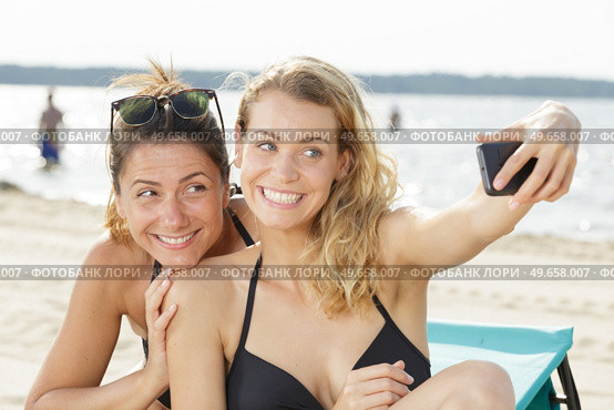 two women do selfie on vacation on the beach. Стоковое фото, агентство Ingram Publishing / Фотобанк Лори