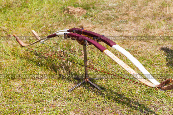 Two wooden traditional handmade bows stand on a holder on a green meadow during the Erdynskie Games, an archery competition among men of the nomadic peoples of Eurasia on Baikal Lake coast. Стоковое фото, фотограф Виктория Катьянова / Фотобанк Лори