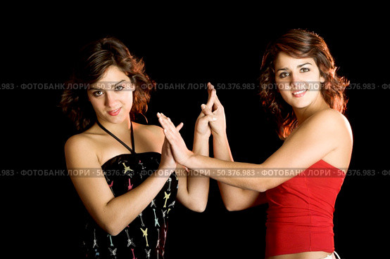 Two young beautiful sisters giving the hands and having fun - This models are true twins. Стоковое фото, агентство Ingram Publishing / Фотобанк Лори