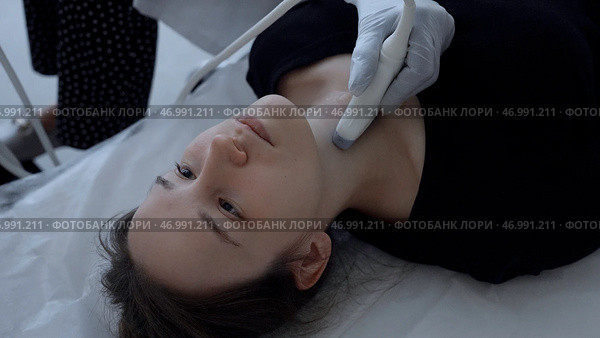 Ultrasound machine doctor conducts examination of thyroid gland of a young woman. Стоковое фото, фотограф David Kashakhi / Фотобанк Лори