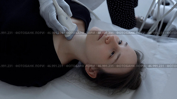 Ultrasound machine doctor conducts examination of thyroid gland of a young woman. Стоковое фото, фотограф David Kashakhi / Фотобанк Лори