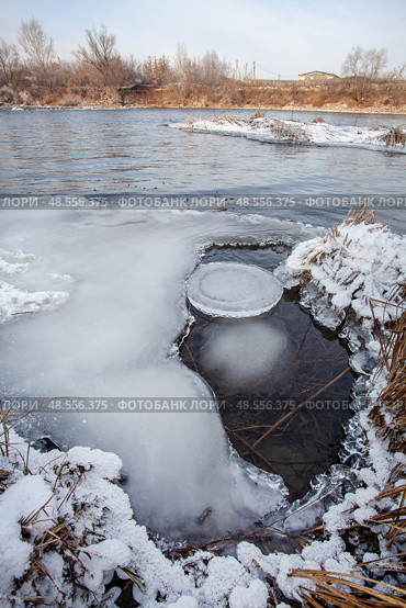 Unfrozen river in winter. Chunks of ice float in the water near the shore. Nearby islets with yellow, dry grass. Стоковое фото, фотограф Андреева Тамара Викторовна / Фотобанк Лори