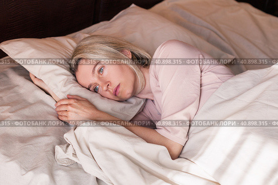 Unhappy sad middle aged woman sitting on bed at home. Стоковое фото, фотограф Гладских Татьяна / Фотобанк Лори