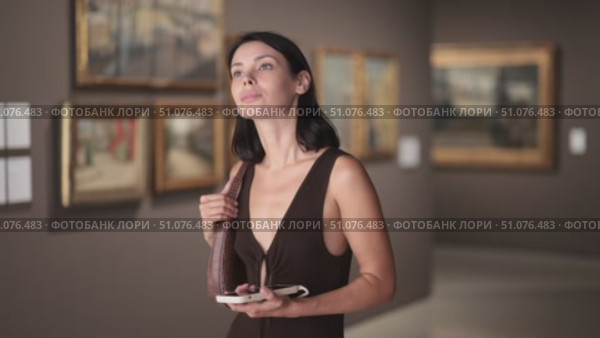 University student visits a museum and an exhibition to prepare for her diploma, she holds mobile phone in hands and uses an online guide. Стоковое видео, видеограф Яков Филимонов / Фотобанк Лори
