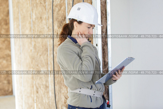 unsure woman builder holding a clipboard. Стоковое фото, агентство Ingram Publishing / Фотобанк Лори