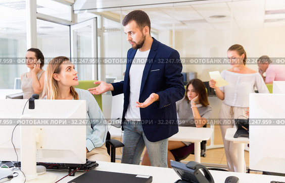 Upset girl sitting at laptop in coworking space while dissatisfied businessman pointing out mistakes in her work. Стоковое фото, фотограф Яков Филимонов / Фотобанк Лори
