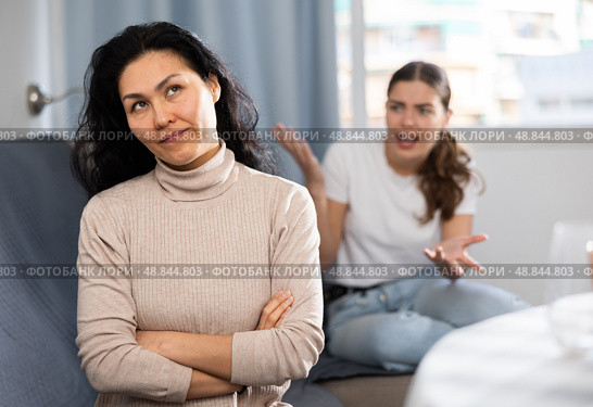 Upset woman sitting at home while girl calming her, asking to forgive after argument. Стоковое фото, фотограф Яков Филимонов / Фотобанк Лори