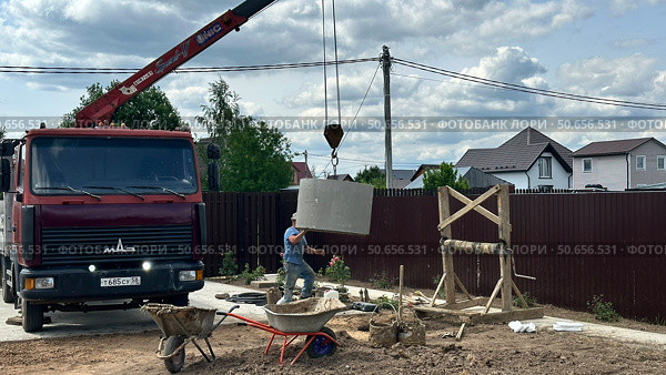 Установка бетонного кольца в шахту колодца с помощью автокрана. Редакционное фото, фотограф Антон Моргунов / Фотобанк Лори