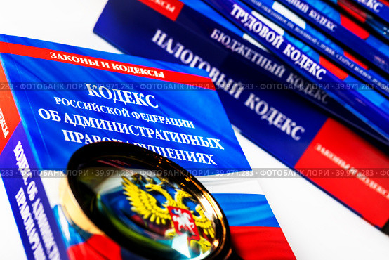 Увеличительное стекло и Кодекс Российской Федерации об административных правонарушениях на белом фоне (2023 год). Редакционное фото, фотограф Николай Винокуров / Фотобанк Лори