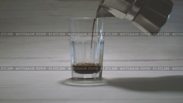 В прозрачную стеклянную чашку, стоящую на светлом фоне, наливают кофе из гейзерной кофеварки. Процесс приготовления вкусного кофе в домашних условиях. Стоковое видео, видеограф Воловодов Владимир / Фотобанк Лори