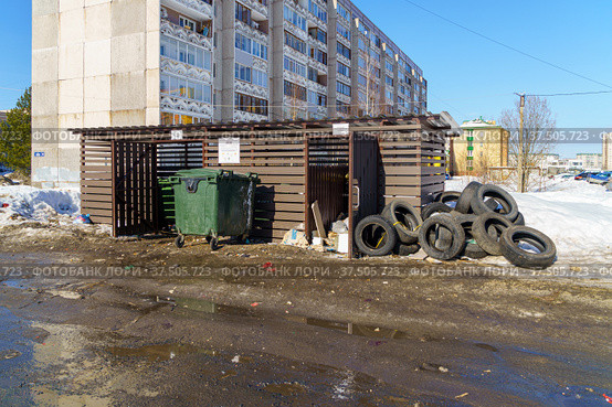 В районе города весной новая помойка закрытого типа с мусорными баками открыта нараспашку и мусор вокруг нее (2022 год). Стоковое фото, фотограф Sergei Gorin / Фотобанк Лори
