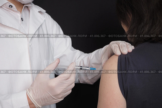Vaccination of the population, covid-19. The doctor vaccinates or injects the patient. Стоковое фото, фотограф Egor Sarantstv / Фотобанк Лори