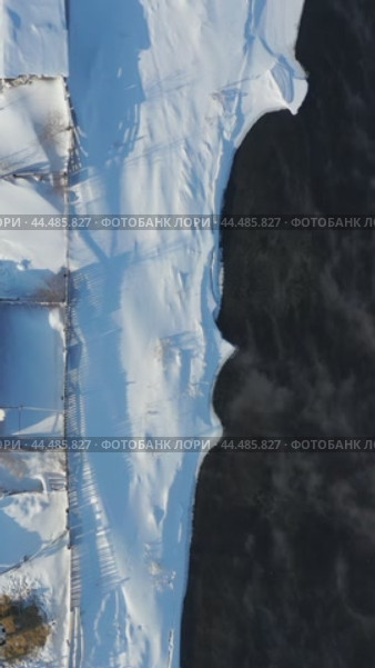 Vertical video from drone on Altai country village Semiletka in winter. Camera looks down. River Koksha with banks covered by snow. Стоковое видео, видеограф Сергей Пристяжнюк (Serg Zastavkin) / Фотобанк Лори