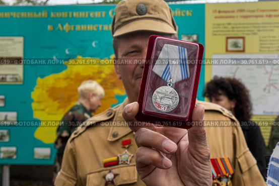 Ветераны Афганской войны держат в руках медаль "30 лет завершения выполнения задач 40 армией в Афганистане" на фоне карты Афганистана в Севастополе, 19 мая 2019 года. Редакционное фото, фотограф Николай Винокуров / Фотобанк Лори
