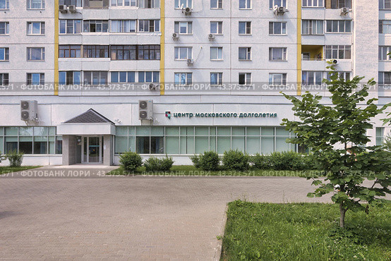 Вход в Центр московского долголетия в подмосковном Зеленограде. Зеленый газон с травой и кустами. Вывеска, кондиционеры на окнах центра и жилых квартир (2024 год). Редакционное фото, фотограф Сергей Никифоров-Гордеев / Фотобанк Лори