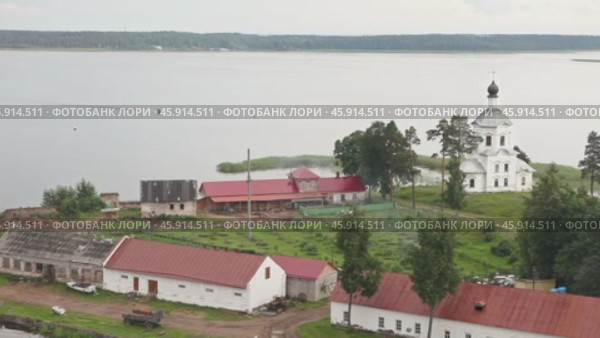 Вид на озеро Селигер, белую церковь, хозяйственные постройки монастыря Нилова пустынь. По воде движется моторная лодка. Стоковое видео, видеограф Сергей Никифоров-Гордеев / Фотобанк Лори