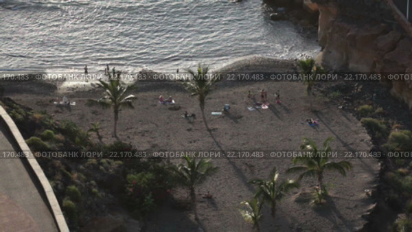 Вид сверху на пляж Playa Las Galgas с отдыхающими и купающимися людьми. Галечный, песчаный пляж на закате. Деревня Playa Paraiso, Тенерифе, Канары, Испания (2016 год). Стоковое видео, видеограф Кекяляйнен Андрей / Фотобанк Лори