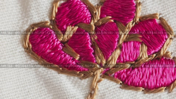 Video of a satin stitch embroidery of a floral ornament with pink flower on a cotton tablecloth. Needlework as a hobby. DIY concept. Top view, macro, flat lay, close-up, mock up. Стоковое видео, видеограф Виктория Катьянова / Фотобанк Лори