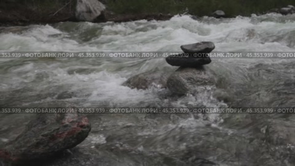 Video of a turbulent flow of water of a mountain river with a stone pyramid. Clean natural water. Стоковое видео, видеограф Виктория Катьянова / Фотобанк Лори