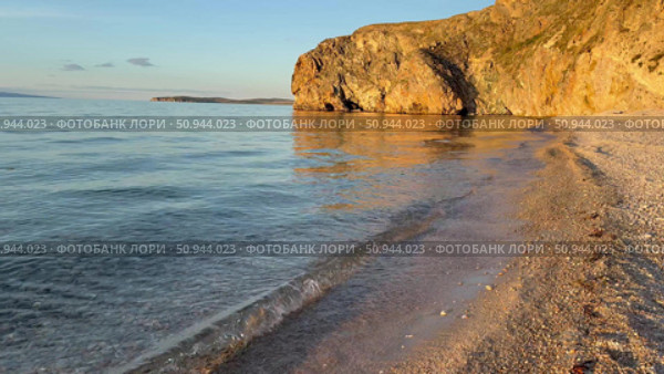 Video of beautiful Baikal Lake at sunset. Olkhon Island. Deserted sandy beach with steep cliffs along shore of Small Sea with pure transparent water in July evening. Natural background. Стоковое видео, видеограф Виктория Катьянова / Фотобанк Лори