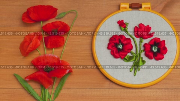 Video of floral hand embroidery with satin ribbons of red poppy flowers in hoops on wooden background. Crafts and embroidery as hobby and leisure. Top view, close-up, flat lay, mock up. Стоковое видео, видеограф Виктория Катьянова / Фотобанк Лори