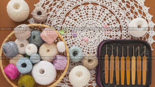 Video of handicraft accessories - set of crochet hooks in case, balls of cotton yarn for crocheting in wicker basket and beautiful handmade lace napkin on wooden table. Flat lay, close-up, top view. Стоковое видео, видеограф Виктория Катьянова / Фотобанк Лори