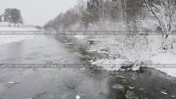 Video of winter landscape with non-freezing Oda River into which natural springs and sources flow. Snow-covered riverbank and forest. Winter travel and walks during New Year and Christmas holidays. Стоковое видео, видеограф Виктория Катьянова / Фотобанк Лори