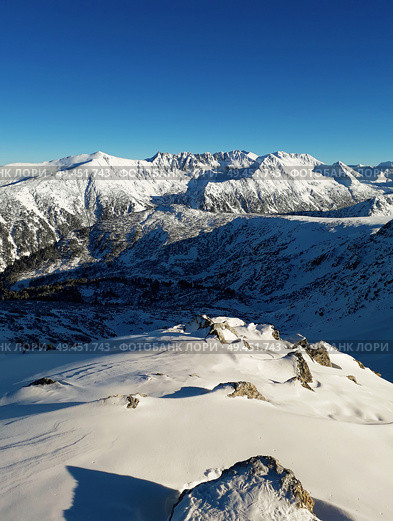 View from the top of Todorka Peak to the Pirin mountains ridge covered by snow in a sunny winter day with blue sky. Стоковое фото, агентство Ingram Publishing / Фотобанк Лори
