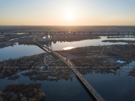 view landscape on the North bridge over the Dnieper River overlooking the Skaimol shopping center and Obolon district, on the left side of Kiev on the sunset, Ukraine. Photo from the drone. North bridge over the Dnieper River overlooking the Skaimol shopping center and Obolon district on the sunset. Стоковое фото, агентство Ingram Publishing / Фотобанк Лори