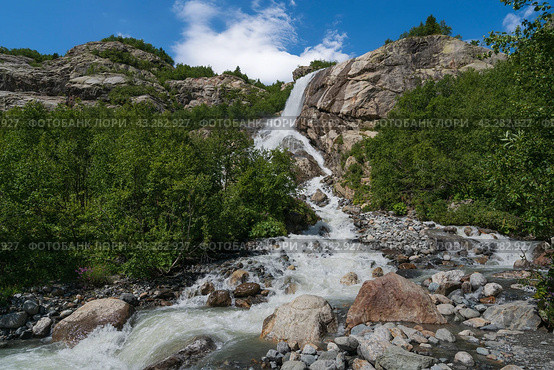 View of the Alibek waterfall formed by the fall of the Jalovchatka River from the Alibek glacier on a sunny summer day, Dombay, Karachay-Cherkessia, Russia. Стоковое фото, фотограф Ula Ulachka / Фотобанк Лори