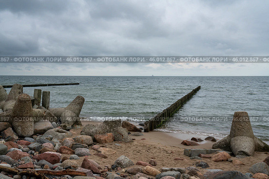 View of wooden breakwaters and concrete tetrapods on the shore of the Baltic Sea on a cloudy summer day, Svetlogorsk, Kaliningrad region, Russia. Стоковое фото, фотограф Ula Ulachka / Фотобанк Лори