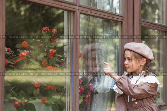 Vintage women's accessories and retro-style clothing. A small, beautiful girl with bows in her hair, in a beige dress and a beret outdoors. Стоковое фото, фотограф Photojuli / Фотобанк Лори