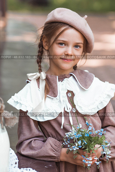 Vintage women's accessories and retro-style clothing. A small, beautiful girl with bows in her hair, in a beige dress and a beret outdoors. Стоковое фото, фотограф Photojuli / Фотобанк Лори