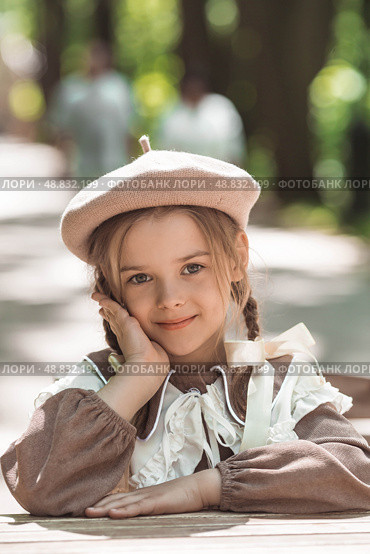 Vintage women's accessories and retro-style clothing. A small, beautiful girl with bows in her hair, in a beige dress and a beret outdoors. Стоковое фото, фотограф Photojuli / Фотобанк Лори