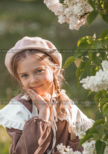 Vintage women's accessories and retro-style clothing. A small, beautiful girl with bows in her hair, in a beige dress and a beret outdoors. Стоковое фото, фотограф Photojuli / Фотобанк Лори