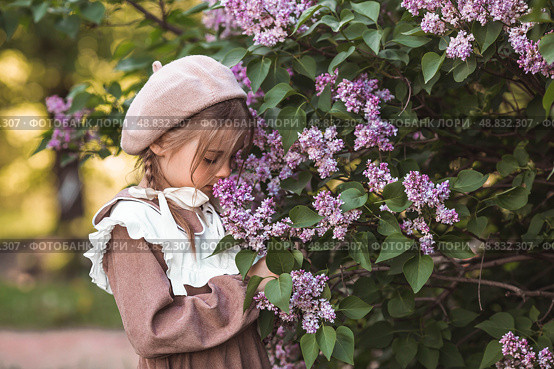 Vintage women's accessories and retro-style clothing. A small, beautiful girl with bows in her hair, in a beige dress and a beret outdoors. Стоковое фото, фотограф Photojuli / Фотобанк Лори