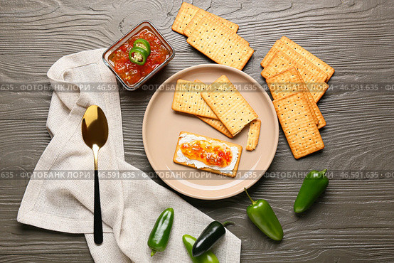 Вкусные крекеры с творогом и вареньем из перца халапеньо в тарелке на сером деревянном столе. Стоковое фото, фотограф Pixel_shot / Фотобанк Лори