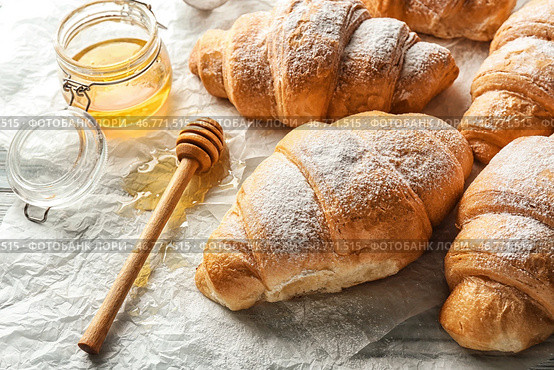 Вкусные круассаны и мед на пергаментной бумаге. Стоковое фото, фотограф Pixel_shot / Фотобанк Лори