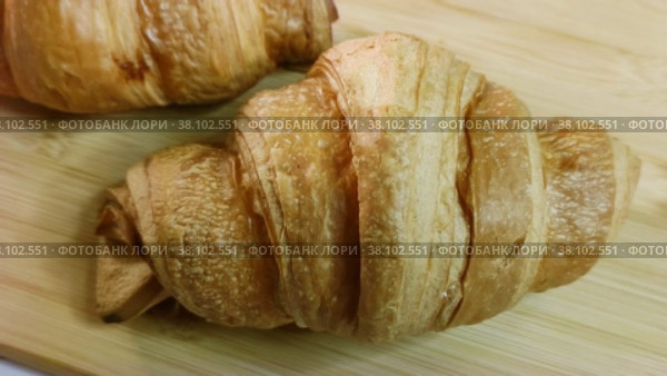 Вкусный хрустящий круассан на деревянной доске крупным планом. Традиционное кондитерское изделие французской кухни. Круассаны с золотистой корочкой для континентального завтрака. Delicious crispy croissant on a wooden board close-up. Traditional confection of French cuisine. Croissants with golden crust for a continental breakfast. Стоковое видео, видеограф Ирина / Фотобанк Лори