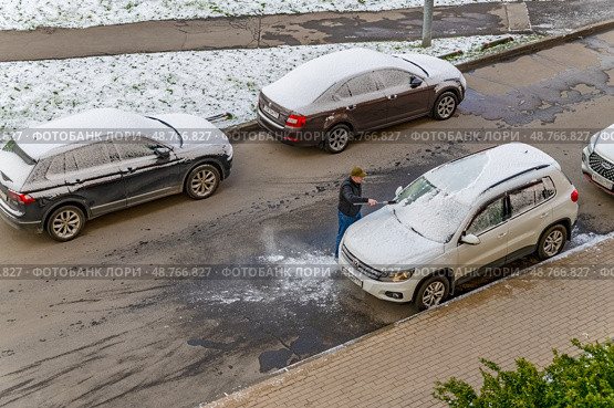 Водитель убирает снег с автомобиля 9 мая 2024 года в Москве. Редакционное фото, фотограф Валерий Иванович Клейменов / Фотобанк Лори