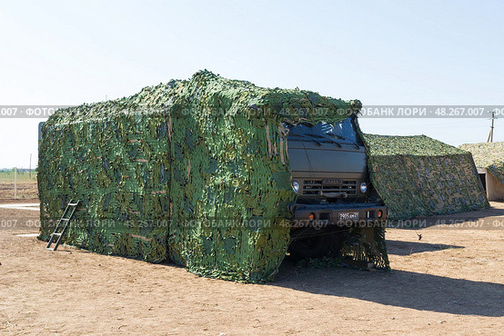 Военный фургон, походная кухня ПАК-200 на шасси автомобиля КАМАЗ-5350, укрытый маскировочной сетью.  Средняя Ахтуба, Волгоградская область, Россия (2021 год). Редакционное фото, фотограф Андрей Цыганков / Фотобанк Лори
