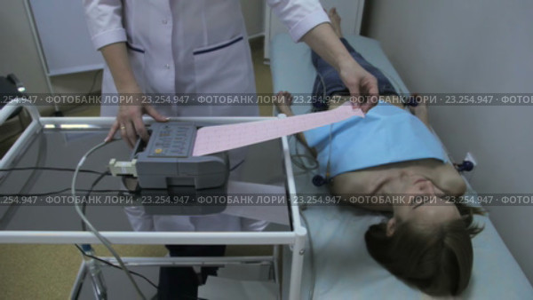 Врач кардиолог смотрит на кардиограмму девушки. Стоковое видео, видеограф Video Kot / Фотобанк Лори