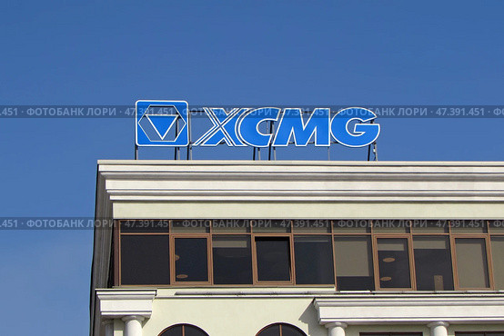 Вывеска и логотип XCMG (Xuzhou Construction Machinery Group Co., Ltd.) на крыше делового здания на фоне синего неба. Редакционное фото, фотограф Цибаев Алексей / Фотобанк Лори