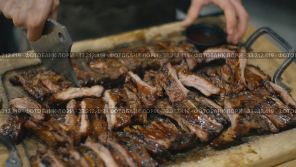 Waiter cuts fried pork ribs. Стоковое видео, видеограф Kozub Vasyl / Фотобанк Лори