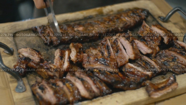 Waiter cuts fried pork ribs. Стоковое видео, видеограф Kozub Vasyl / Фотобанк Лори
