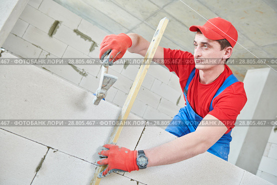 walling. bricklayer installing wall from autoclaved aerated concrete blocks. Стоковое фото, фотограф Дмитрий Калиновский / Фотобанк Лори