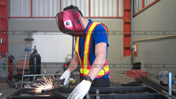 Warehouse worker wear hard hats to protect from welding glare, Welding steel parts of a building structure in a factory. Стоковое фото, агентство Ingram Publishing / Фотобанк Лори