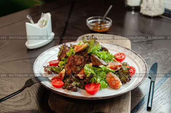 warm chicken liver salad with figs is served on a white plate with a sauce of French mustard and honey. Close up. Стоковое фото, фотограф Оксана Медведева / Фотобанк Лори