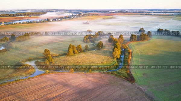 Warm sunny September morning. Autumn beautiful fog landscape. Small river curves in trees. Bright sunny misty riverside. Scenic view of rural sunrise. Village in Agriculture fields. Europe, Belarus. Стоковое фото, агентство Ingram Publishing / Фотобанк Лори
