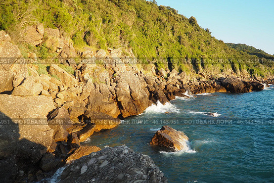 Waves gently crash against the rugged rocks while the sun sets over the horizon. Experience the serene beauty of this coastal location filled with natural wonders. Canj, Montenegro, Adriatic sea (2024 год). Стоковое фото, фотограф Юлия Петровская / Фотобанк Лори